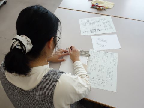 体験会参加者の点字体験の様子の写真。点字板と点筆を使い点字を打っている。