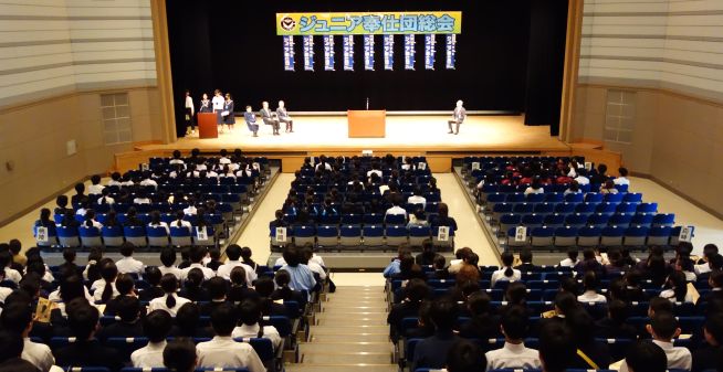 ジュニア奉仕団総会の様子。壇上には向かって右に小牧市教育委員会教育長、左に小牧市社会福祉協議会会長、ジュニア奉仕団世話人会会長と副会長が着席。