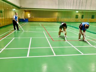 障がい者スポーツのひとつであるボッチャのコートのライン引きをしている様子の写真。一寸奉仕こまきの会員3人がスポーツ広場で白いテープを使ってラインを引いている。
