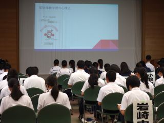 全体会の様子の写真。ボランティアセンター所長から注意事項などの話があり、中高生たちは手元の資料を確認している。