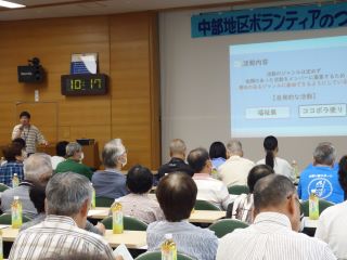 小牧中部地区つどいの写真。プロジェクターでココボラの活動内容を映し、来場者はその画像を見ながら、ココボラの冨板氏の話を聞いている。