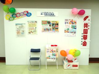 昨年度開催時の写真。赤い羽根共同募金のブースで募金箱や赤い羽根についての掲示物が白い壁に貼ってある。