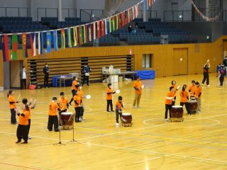 バリアフリー和太鼓サークル鼓っこの写真。23名が和太鼓やチャッパなどを持って楽しく演奏している。