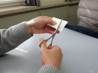 折り線や切り線がすでに書かれている牛乳パックをハサミで切っている写真。