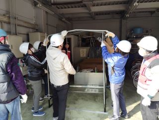 災害ボランティアの実習の写真。数人で仮設トイレの骨組みを組み立てている様子。