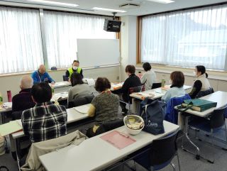 災害ボランティアとの意見交換の写真。視聴覚室で、受講者8名とボランティア2名が向かい合って座って話をしている様子。