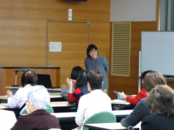 講師の桐林氏の写真。60代の女性。参加者の皆さんに笑顔であいさつをしている様子。
