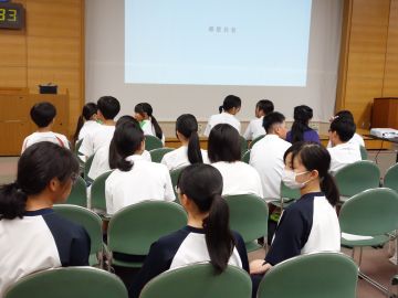 椅子に座っている生徒たちが近くの人同士で映画を観た感想を話し合っている様子の写真。