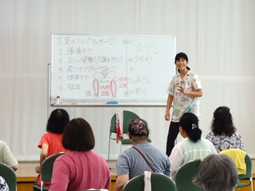 講師のアップ写真。壇上で、ホワイトボードの横に講師が笑顔で立って参加者に話をしている。