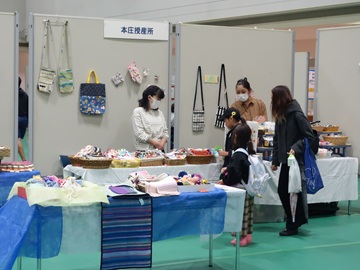昨年の様子の写真。福祉施設のブースに立ち寄った親子が商品を見ている。